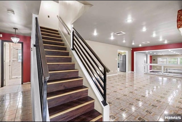 staircase with an inviting chandelier