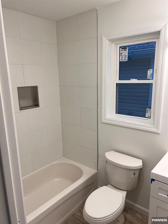 full bathroom featuring vanity, wood-type flooring, tiled shower / bath combo, and toilet