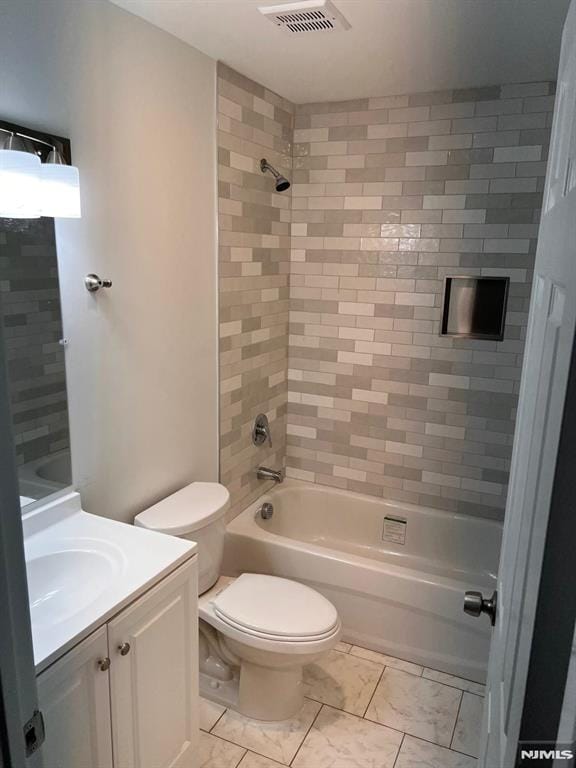 full bathroom featuring tiled shower / bath combo, toilet, and vanity