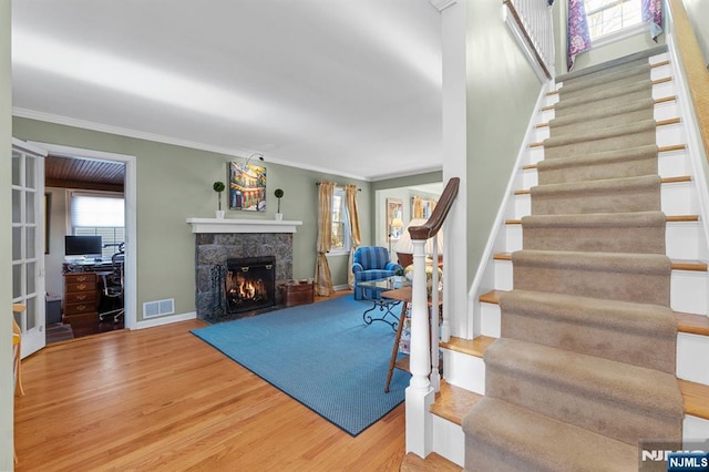 interior space featuring crown molding, wood-type flooring, and a fireplace