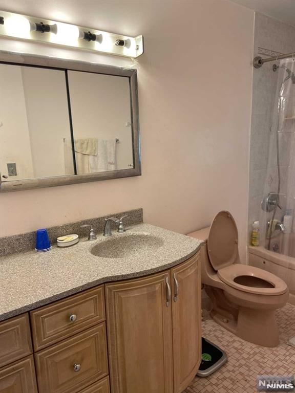 full bathroom with tile patterned floors, shower / bathtub combination with curtain, vanity, and toilet