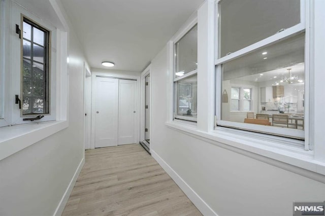 corridor featuring light hardwood / wood-style floors and a notable chandelier