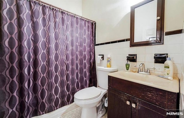 bathroom with tile walls, vanity, and toilet