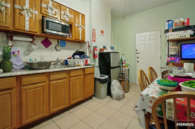 kitchen with fridge, light tile patterned floors, tasteful backsplash, and sink