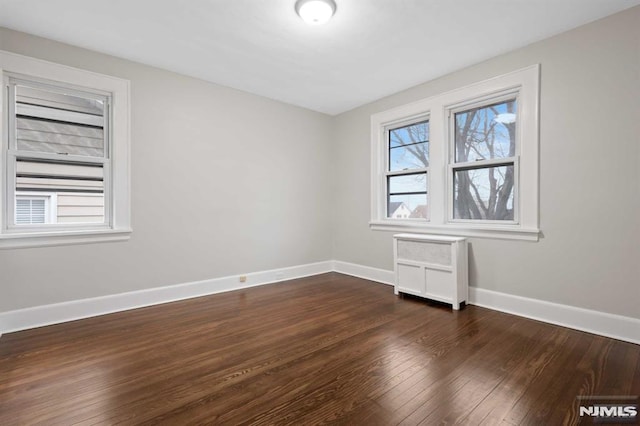 unfurnished room with radiator and dark wood-type flooring