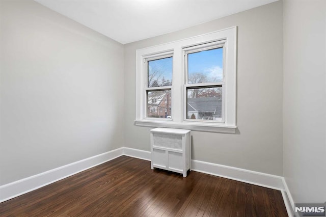 spare room with radiator and dark hardwood / wood-style flooring