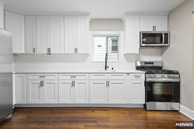 kitchen featuring dark hardwood / wood-style flooring, white cabinetry, sink, and appliances with stainless steel finishes