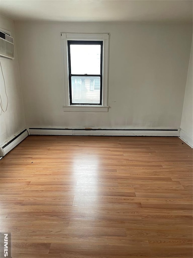 empty room featuring light hardwood / wood-style flooring and a baseboard heating unit