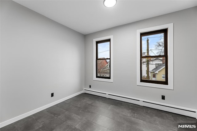 empty room featuring a baseboard radiator and plenty of natural light