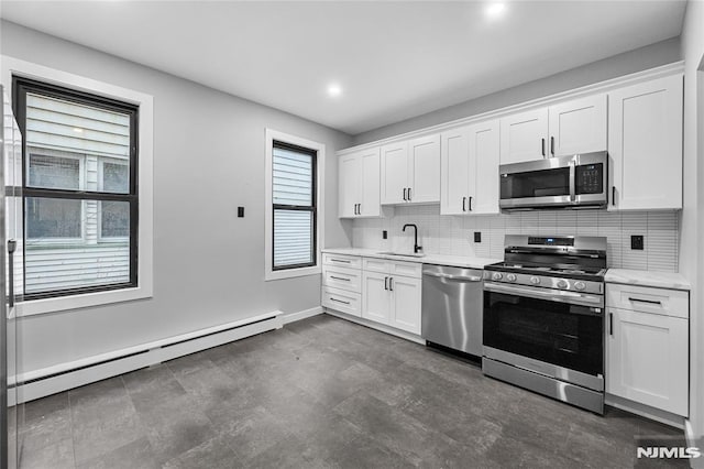 kitchen featuring sink, a baseboard radiator, a healthy amount of sunlight, white cabinetry, and stainless steel appliances