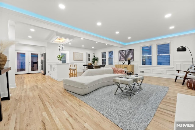 living room with french doors, light wood-type flooring, and crown molding