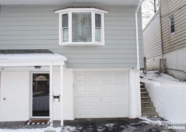 snow covered property entrance featuring a garage