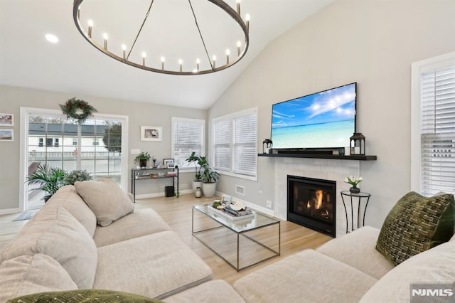 living room with light hardwood / wood-style flooring, lofted ceiling, and a chandelier