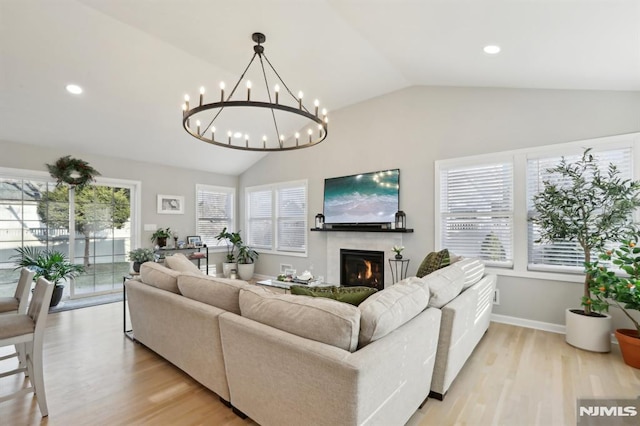 living room with light hardwood / wood-style flooring, lofted ceiling, and a notable chandelier