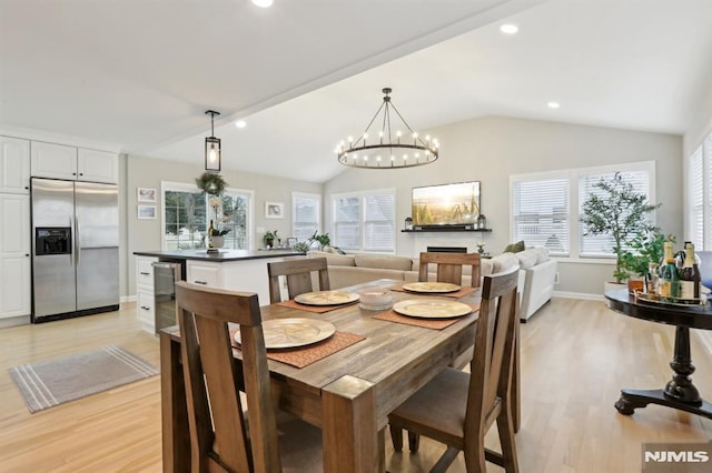 dining space with lofted ceiling, a chandelier, and light hardwood / wood-style flooring