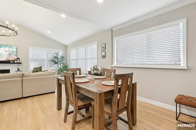 dining area with vaulted ceiling, a notable chandelier, and light hardwood / wood-style floors