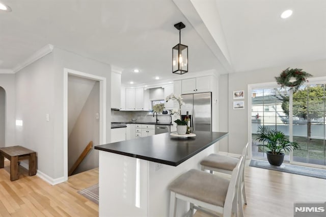 kitchen featuring tasteful backsplash, light hardwood / wood-style floors, pendant lighting, stainless steel appliances, and white cabinets