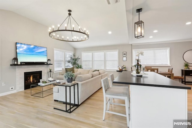 living room with lofted ceiling, a chandelier, and light hardwood / wood-style flooring