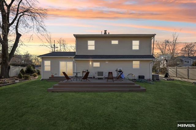 back house at dusk with a wooden deck, a yard, and central AC