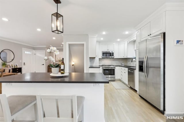 kitchen with tasteful backsplash, pendant lighting, white cabinetry, appliances with stainless steel finishes, and a kitchen breakfast bar