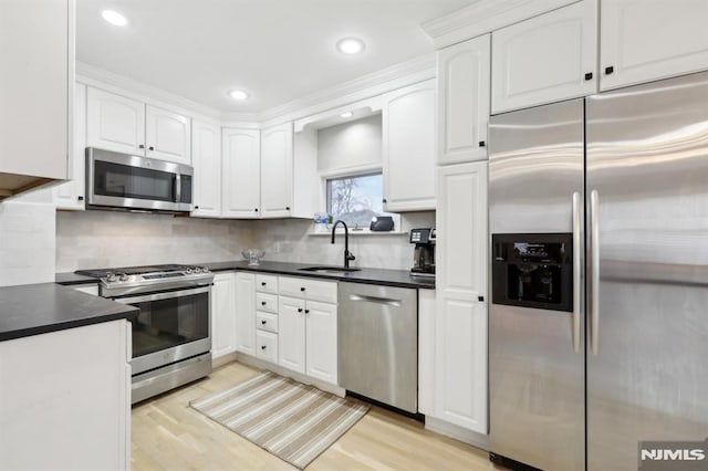 kitchen featuring stainless steel appliances, light hardwood / wood-style flooring, white cabinetry, and sink