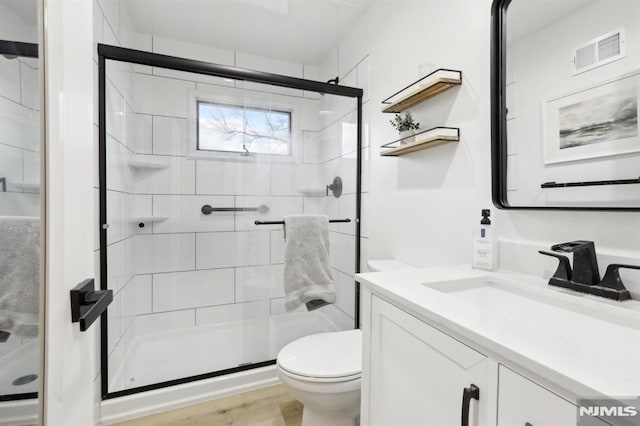 bathroom with toilet, vanity, a shower with door, and hardwood / wood-style flooring