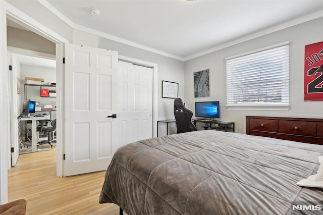 bedroom with light hardwood / wood-style floors, a closet, and ornamental molding