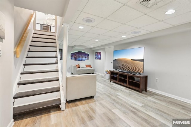 living room featuring a drop ceiling and light wood-type flooring