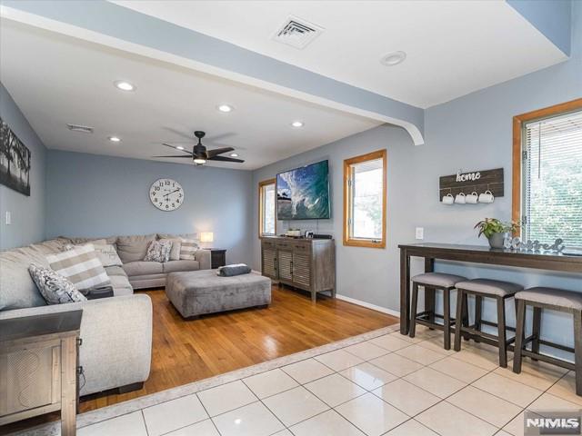 living room with ceiling fan, beam ceiling, and light tile patterned floors