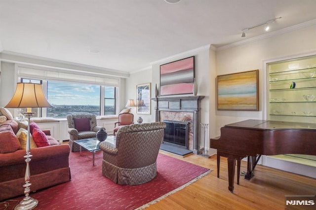 living room featuring wood-type flooring, a premium fireplace, crown molding, and track lighting