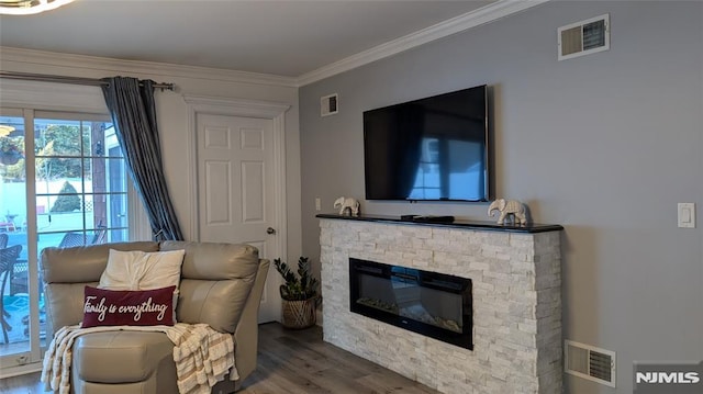 sitting room featuring a stone fireplace, crown molding, and wood-type flooring