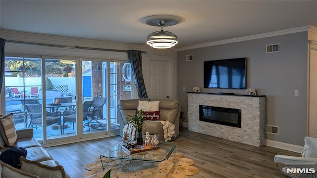 living room with wood-type flooring, a fireplace, and ornamental molding