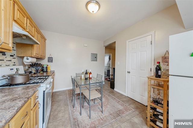 kitchen with light brown cabinetry, stainless steel gas stove, white fridge, and light tile patterned floors