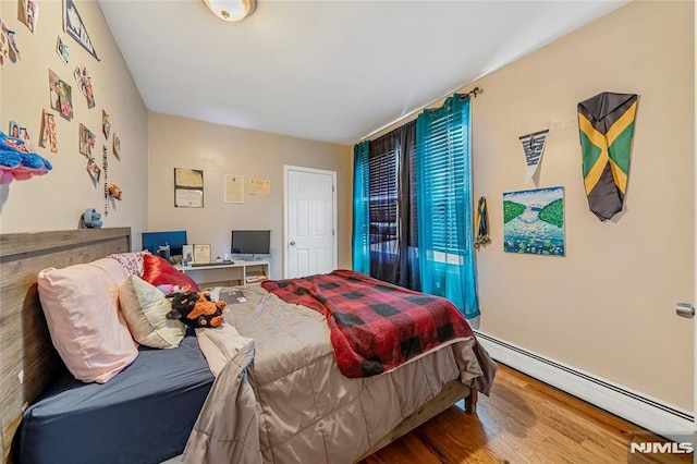 bedroom featuring baseboard heating and wood-type flooring