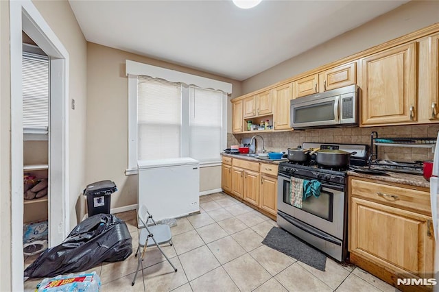 kitchen featuring decorative backsplash, light tile patterned floors, stainless steel appliances, and light brown cabinetry