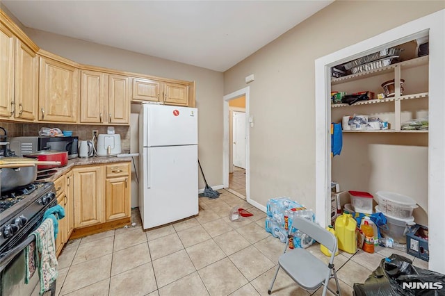 kitchen with black appliances, light brown cabinets, light tile patterned floors, and tasteful backsplash