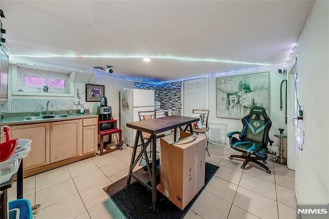 kitchen with light brown cabinetry, white refrigerator, light tile patterned floors, and sink