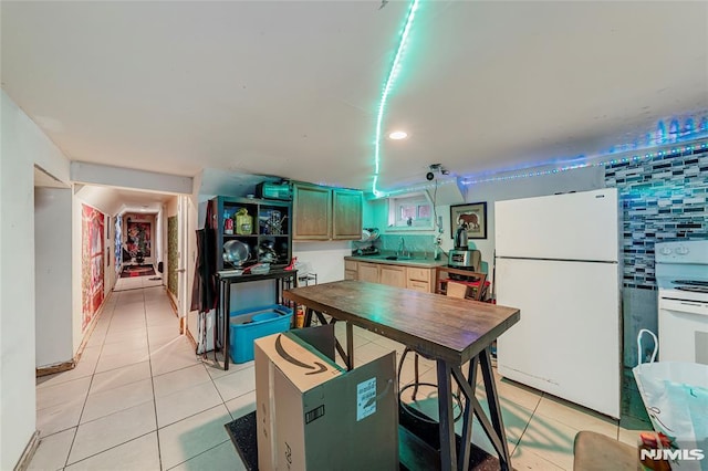 kitchen featuring light tile patterned flooring, white appliances, kitchen peninsula, and sink