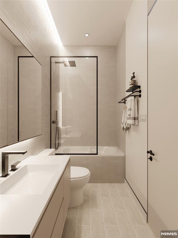 full bathroom with toilet, tile patterned flooring, tiled shower / bath combo, and vanity