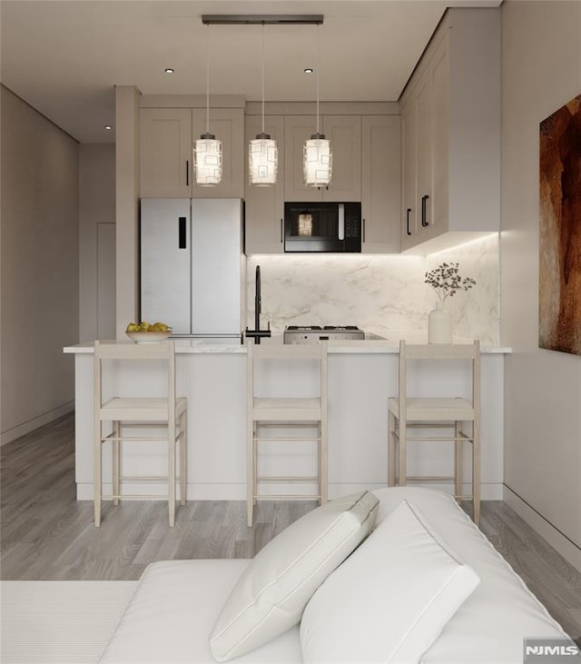 kitchen featuring light hardwood / wood-style floors, tasteful backsplash, fridge, a kitchen breakfast bar, and pendant lighting