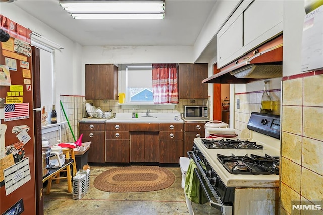 kitchen featuring dark brown cabinetry, sink, refrigerator, decorative backsplash, and white gas range oven