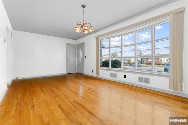 spare room featuring hardwood / wood-style floors and an inviting chandelier