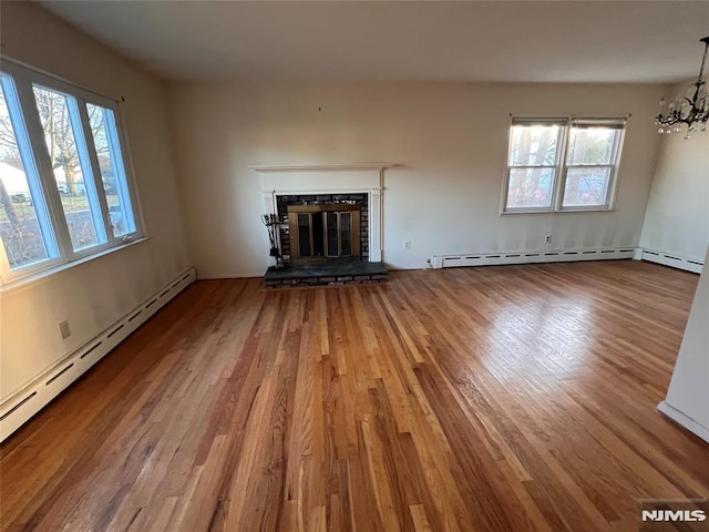 unfurnished living room with a fireplace, hardwood / wood-style flooring, plenty of natural light, and a baseboard heating unit