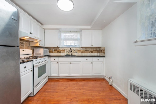 kitchen with white appliances, light hardwood / wood-style floors, white cabinetry, and radiator