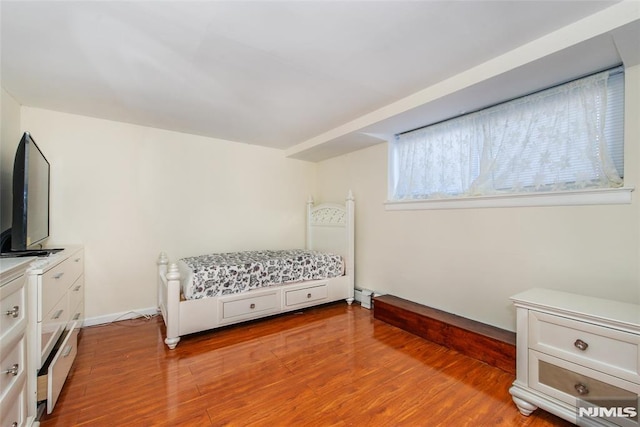 bedroom featuring light hardwood / wood-style flooring and a baseboard heating unit