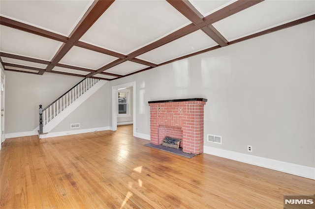 unfurnished living room with light wood-type flooring, a brick fireplace, coffered ceiling, a baseboard radiator, and beam ceiling