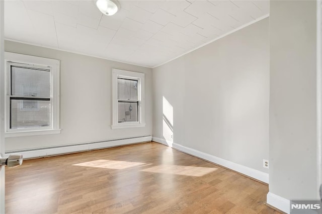 spare room with a baseboard heating unit, ornamental molding, and wood-type flooring