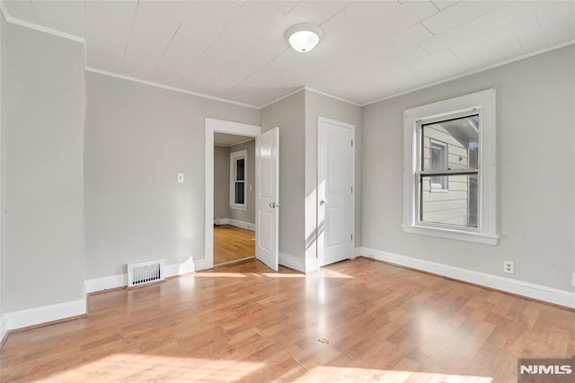 empty room with ornamental molding and light hardwood / wood-style flooring