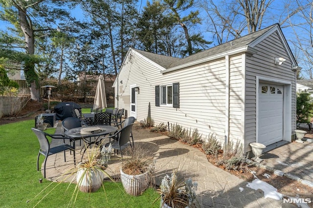 exterior space featuring a patio area, a garage, and a lawn