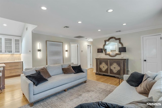 living room with ornamental molding and light hardwood / wood-style flooring